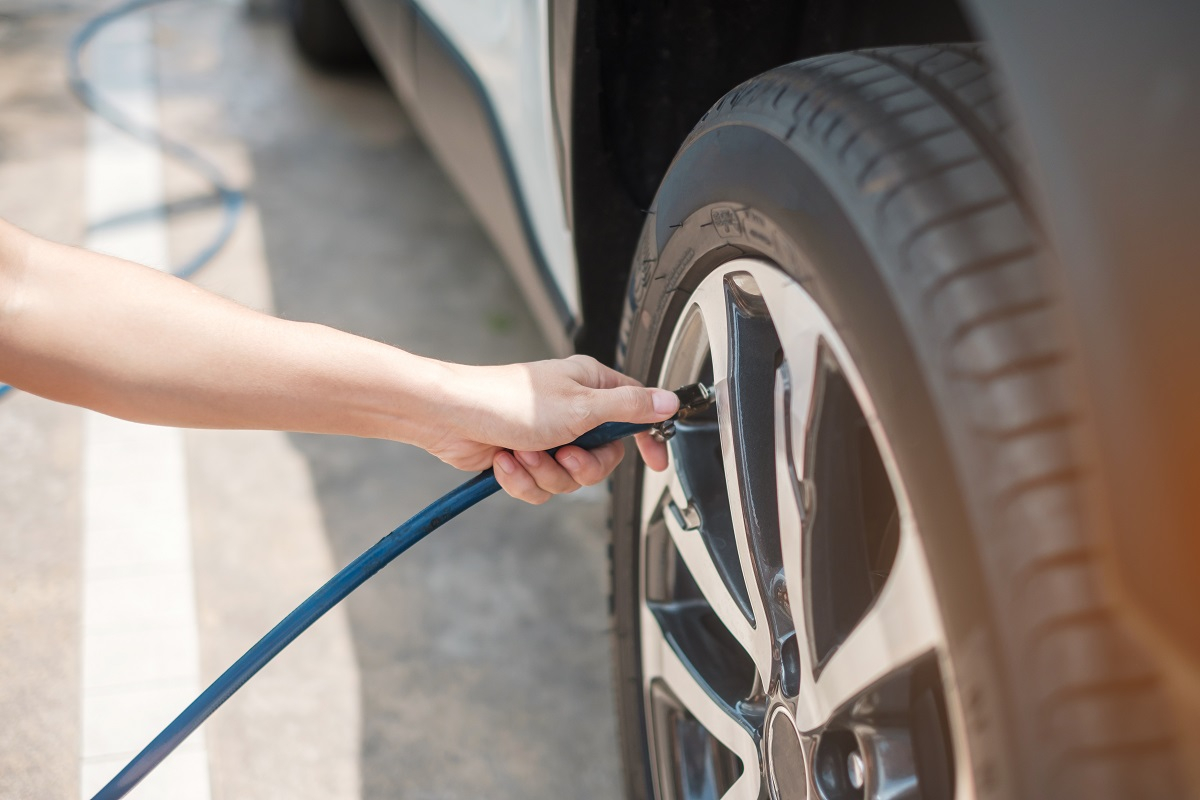 personne vérifiant la pression des pneus de sa voiture