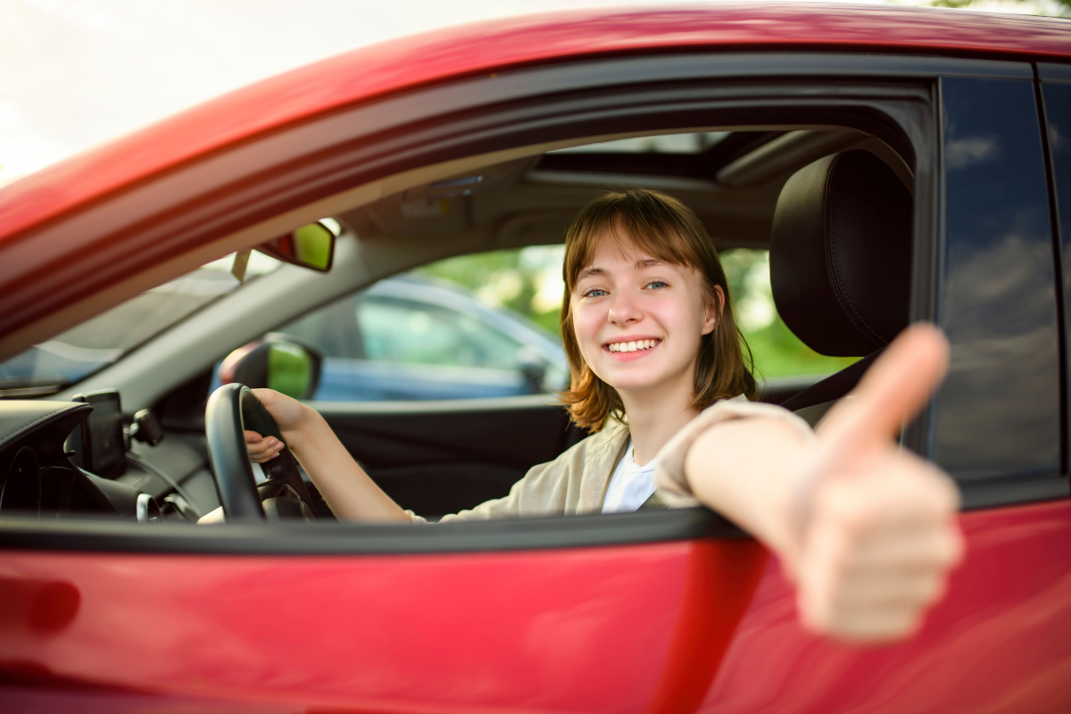 Jeune fille heureuse en voiture ayant passé son permis en le finançant grâce aux aides de sa région