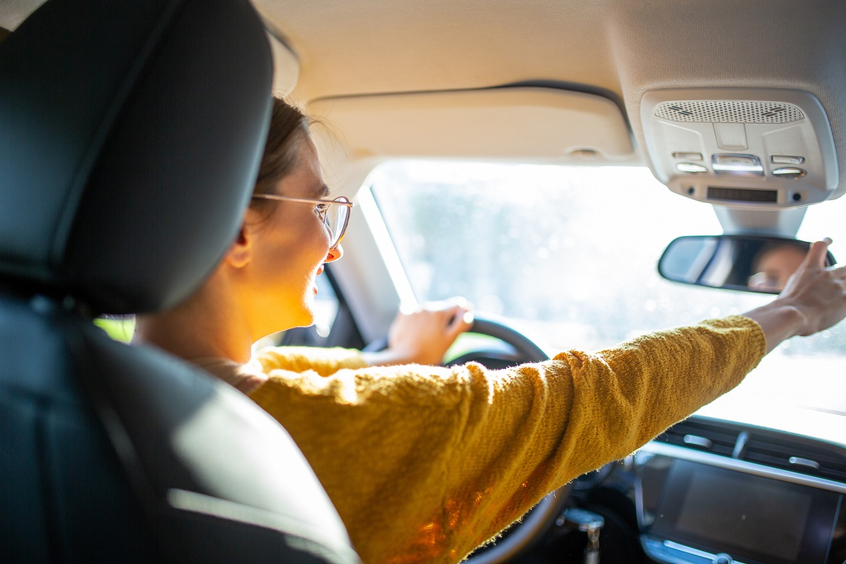 jeune fille qui règle son rétroviseur avant de conduire